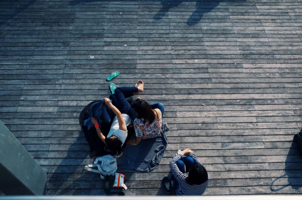 three teens sitting on stone payment