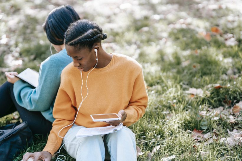 listeningtopod two young people sitting on grass wearing earbuds